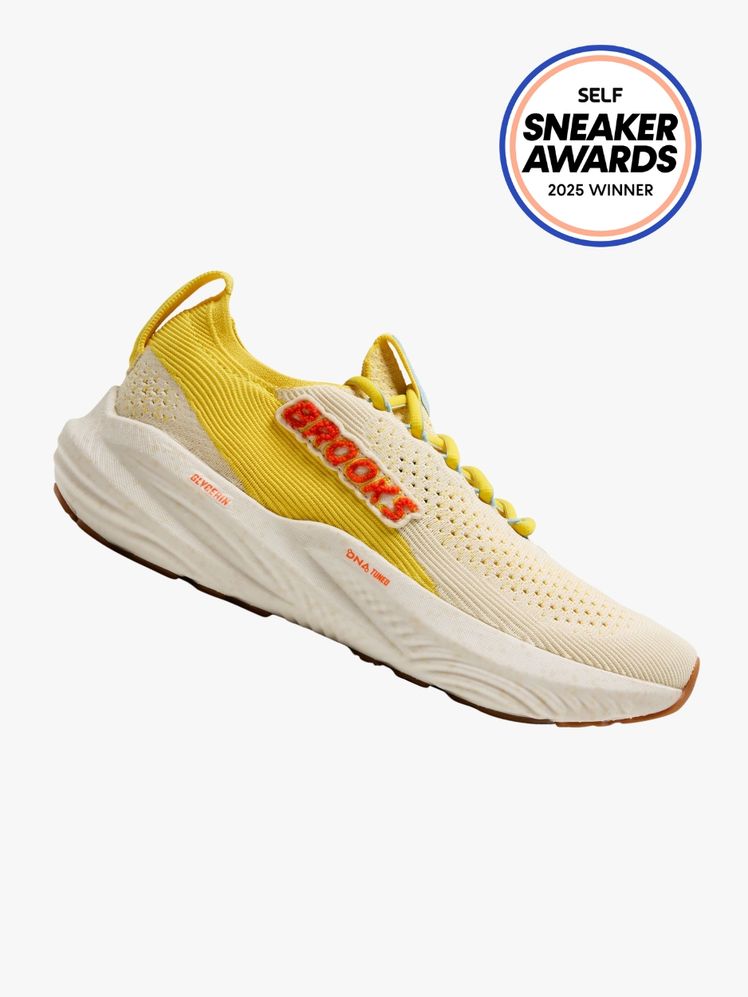 Brooks Glycerin StealthFit 22 sneaker in offwhite and mustard yellow with an orange embroidered logo. The SELF Sneaker...