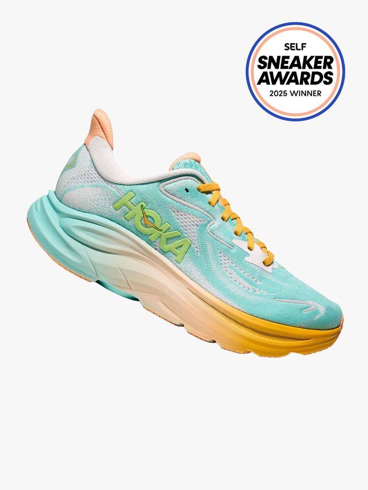 HOKA Clifton 10 sneaker in light blue blush and orange color way and green HOKA logo. The SELF Sneaker Awards seal is in...